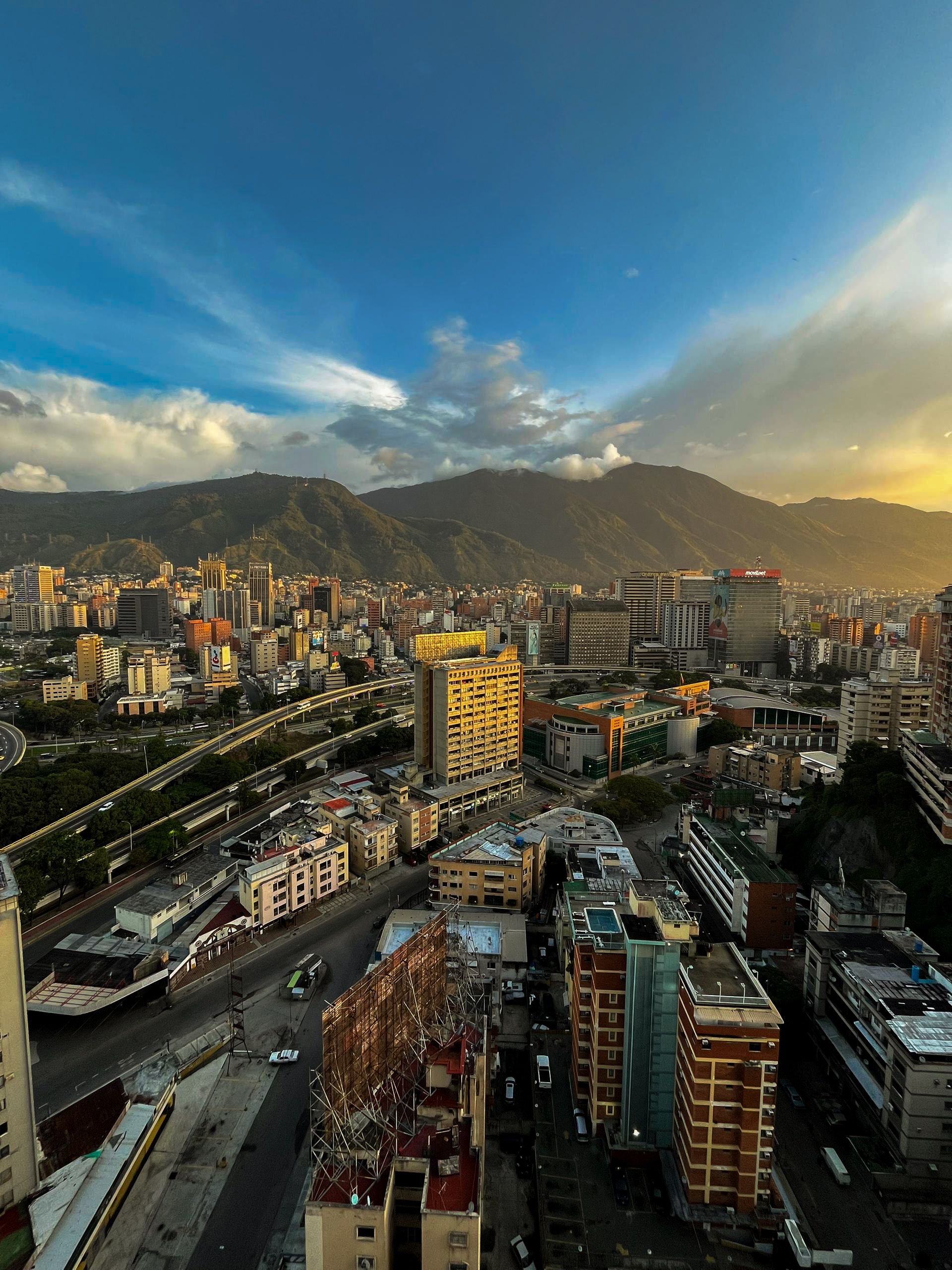 Vista aérea del horizonte de Caracas, capital de Venezuela, al atardecer, con los edificios de la ciudad frente a la cordillera de El Ávila
