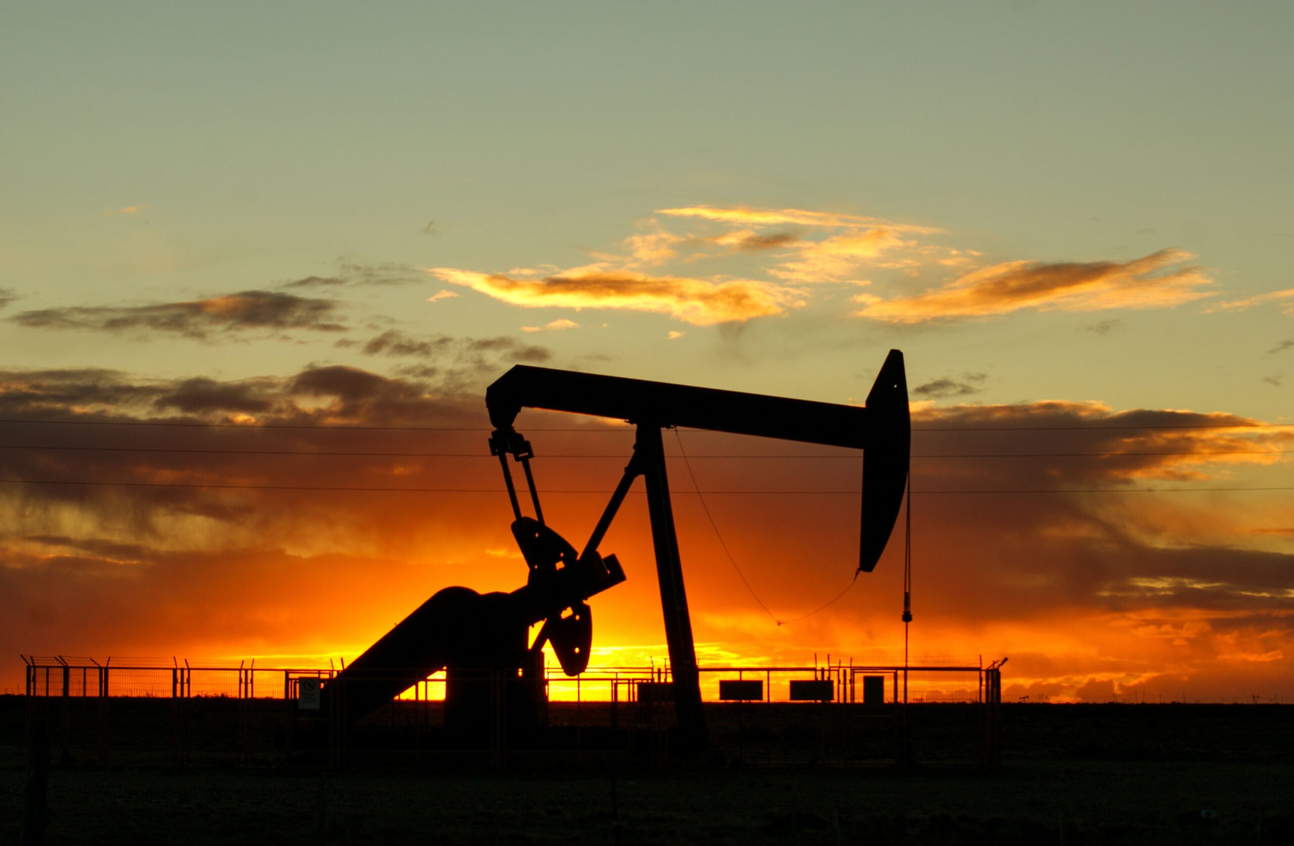 Silueta de un balancín de bombeo petrolero al atardecer, símbolo de la industria de hidrocarburos que sostiene la economía venezolana